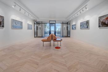 A room with a wooden floor and a bench with a red cushion.